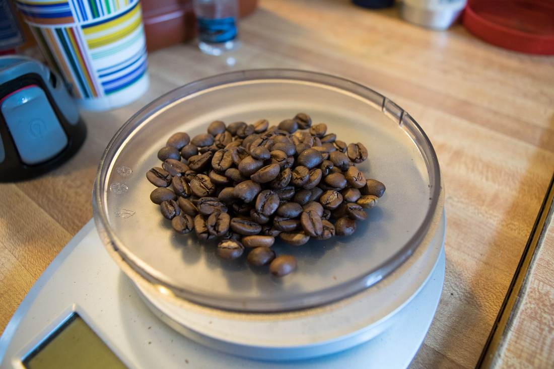 Granos de café tostado sobre el plato de una báscula de cocina.
